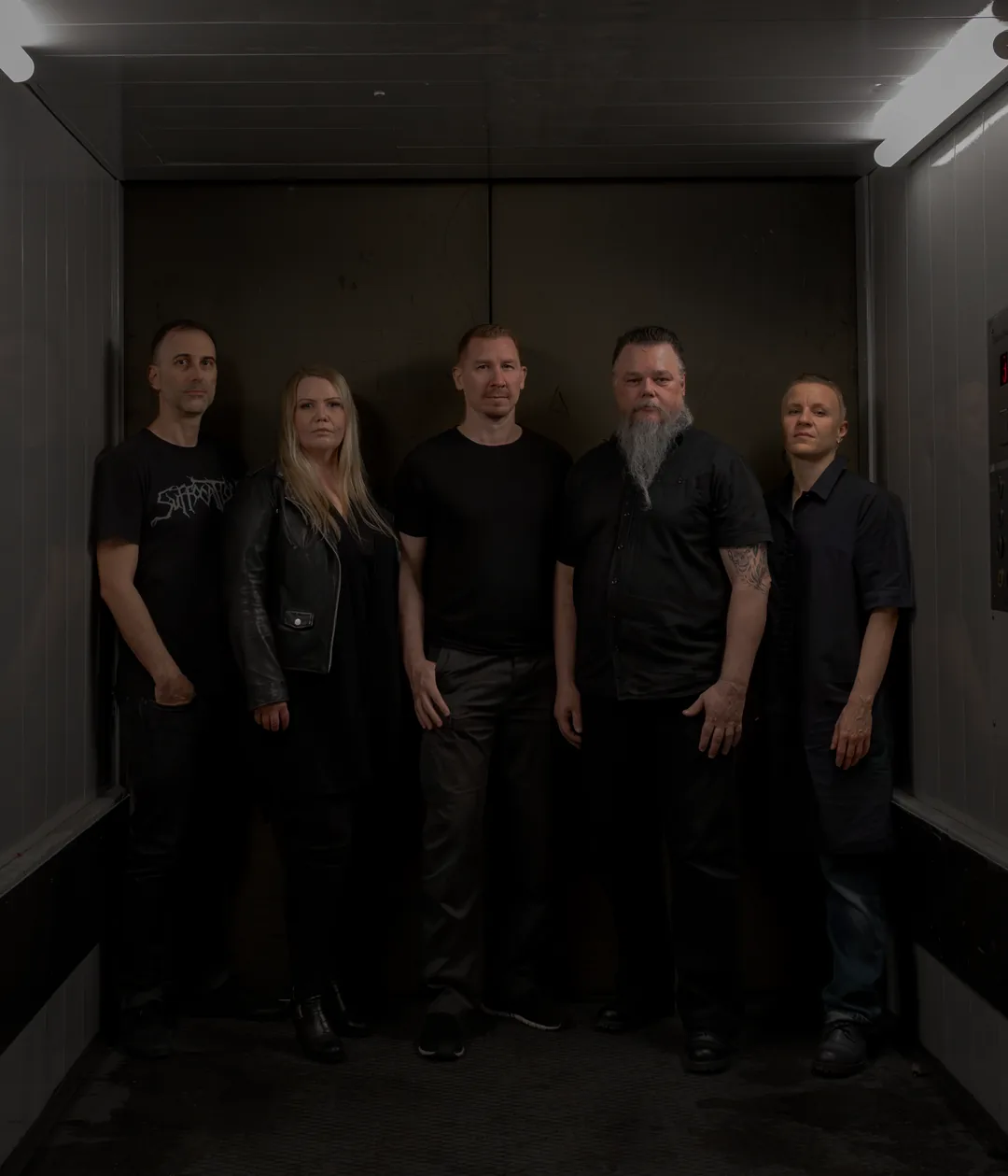 Kalmo, five members standing in a dim freight elevator