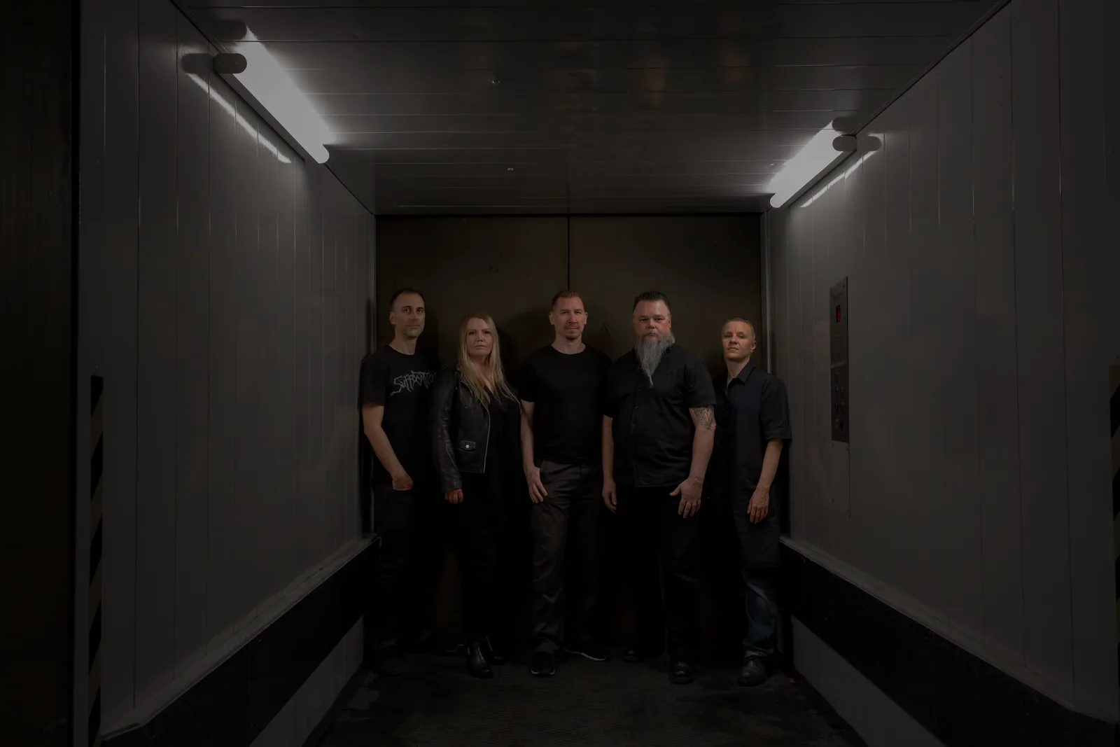 Kalmo, five members standing in a dim freight elevator